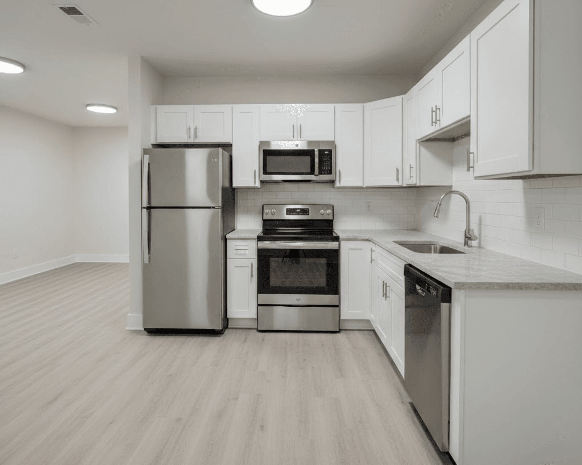 Modern rental unit kitchen with white cabinets and stainless appliances